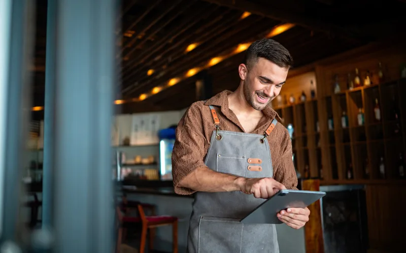 A waiter using a tablet to manage service in a modern restaurant